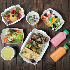 Dietary food in containers with you. Food delivery. Breakfast, lunch and dinner. On a wooden background. The food assortment is calculated in calories. Take with you. Healthy diet.