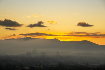 Fototapeta premium Sunrise and sunset, beautiful clouds over the meadow, hills and buildings in the town. Slovakia