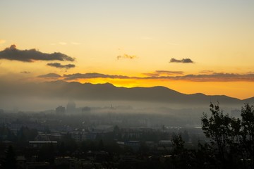 Sunrise and sunset, beautiful clouds over the meadow, hills and buildings in the town. Slovakia