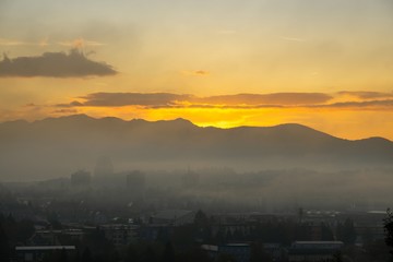 Sunrise and sunset, beautiful clouds over the meadow, hills and buildings in the town. Slovakia