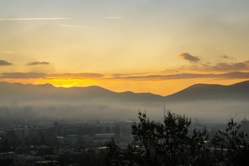 Sunrise and sunset, beautiful clouds over the meadow, hills and buildings in the town. Slovakia