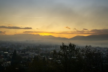 Sunrise and sunset, beautiful clouds over the meadow, hills and buildings in the town. Slovakia