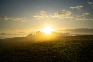 Sunrise and sunset, beautiful clouds over the meadow, hills and buildings in the town. Slovakia