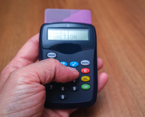 Close up of human hand making a card payment using a remote machine with intentional focus on the hand, leaving the machine in soft focus