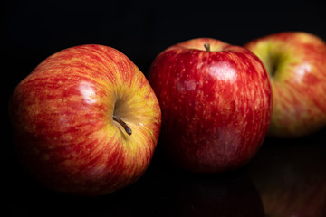 Arrangement with fruits on a shiny black surface with black background.