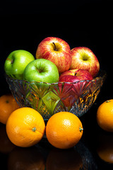 Arrangement with fruits on a shiny black surface with black background.