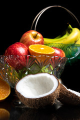 Arrangement with fruits on a shiny black surface with black background.