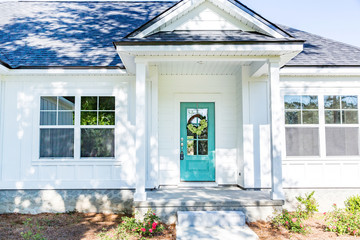 Exterior facade of a white new construction house with a vibrant turquoise front door © Ursula Page