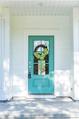 Exterior facade of a white new construction house with a vibrant turquoise front door