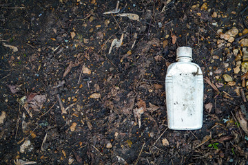 White dirty plastic bottle on ground, environmental pollution. Copy space.