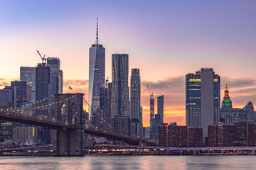 Fototapeta na wymiar Sunset time cityscape Manhattan.A lot of business buildings in line.Light of the city it turn on. Color sky very awesome. point view from Dumbo Brooklyn. Selective focus.