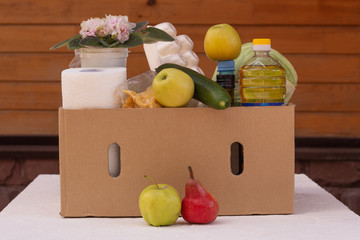 A box of groceries in the courtyard of the house. Fresh vegetables and food are delivered to your home.