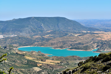 Fototapeta na wymiar lago azul rodeado de montañas y vegetación