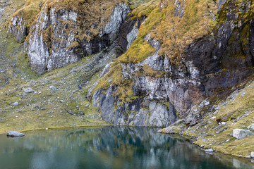 colorful rocky shore mirror reflection in calm Balea mountain lake 