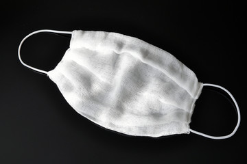 Gauze bandages with elastic bands over the ears, made at home, on a black background. Respiratory protection.