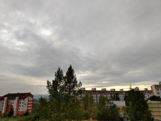 Obraz premium Sunrise and sunset, beautiful clouds over the meadow, hills and buildings in the town. Slovakia