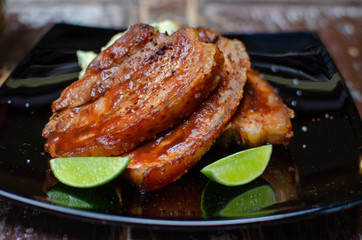 Grilled pork loin with lemon and on a black plate