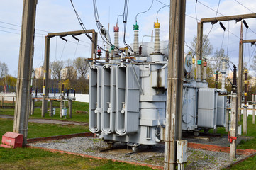 Fototapeta na wymiar Large industrial iron metal transformer substation with transformers and high-voltage electrical equipment and wires with surge arresters to supply the city with electricity