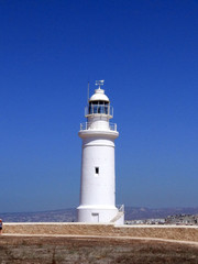 Fototapeta na wymiar White lighthouse against the blue sea and sky. Summer landscape.