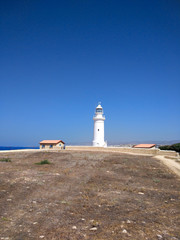 White lighthouse against the blue sea and sky. Summer landscape.