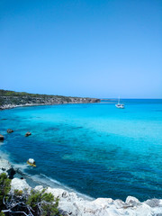 Turquoise sea with white sand and a white boat in the distance. Beautiful summer landscape.