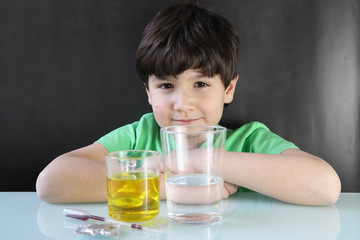 Niño realizando un experimento casero durante la cuarentena por coronavirus, es una lámpara de lava con agua, aceite, colorante, pastilla efervescente paso 1 :ingredientes