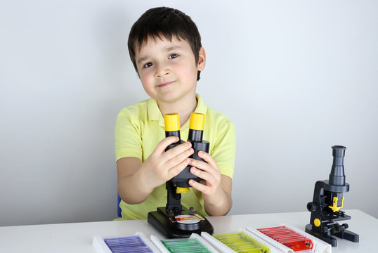 ni&ntilde;o con microscopio y y lupa binocular mirando muestras biol&oacute;gicas preparadas en portaobjetos