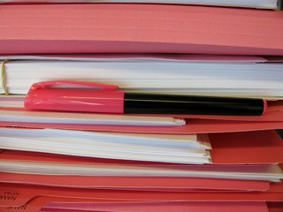 Stack of pink folders and marker