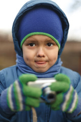 Portrait of the caucasian cute little cheerful child boy hold photo camera. Compact photographer doing taking the picture.