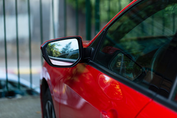 side rear-view mirror red car on street background