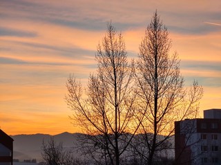 Sunrise and sunset, beautiful clouds over the meadow, hills and buildings in the town. Slovakia
