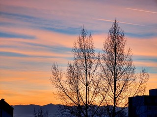 Naklejka premium Sunrise and sunset, beautiful clouds over the meadow, hills and buildings in the town. Slovakia