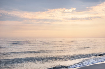 Beautiful sunset over the calm sea on a cloudy hot summer evening.