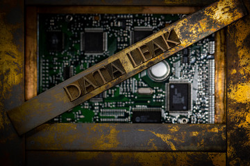 Photo of real authentic typeset letters forming Data Leak text on vintage textured grunge copper background and green computer switchboard 