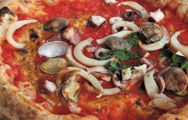 Traditional Italian sea food pizza with basil 