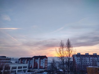 Fototapeta premium Sunrise and sunset, beautiful clouds over the meadow, hills and buildings in the town. Slovakia