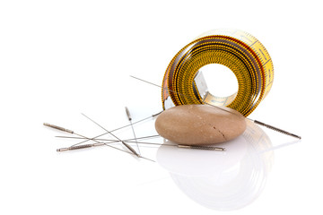 Yellow measuring tape isolated on white background. Measuring tape with needles for acupuncture. Caring for health and body shape, traditional Chinese acupuncture and massage. Close-up.