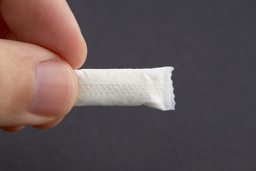 caucasian person holds snus tobacco pouch over black background. copy space. alternative chewing...