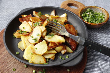 Fried potatoes in a cast iron pan on a gray background