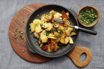 Fried potatoes in a cast iron pan on a gray background.