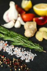 Selective focus. Set spice on a black stone board. Peppers mix, Himalayan salt, rosemary, garlic, lemon, ginger, red orange. Spices for fish or meat. Spices for marinade. Spices for a healthy diet.