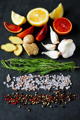 Obraz na płótnie Canvas Selective focus. Set spice on a black stone board. Peppers mix, Himalayan salt, rosemary, garlic, lemon, ginger, red orange. Spices for fish or meat. Spices for marinade. Spices for a healthy diet.