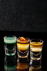 3 shots alcohol drink on black glossy table with space for text. High quality photo of cocktails. Top