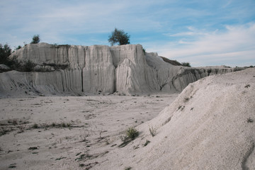 White limestone rock on an old abandoned quarry. White landscape. Limestone blurred by the rain. White rock against the blue sky.