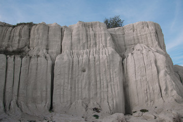 White limestone rock on an old abandoned quarry. White landscape. Limestone blurred by the rain. White rock against the blue sky.