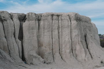 White limestone rock on an old abandoned quarry. White landscape. Limestone blurred by the rain. White rock against the blue sky.