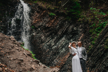 bride and groom in the mountains against the backdrop of a waterfall. mountain wedding