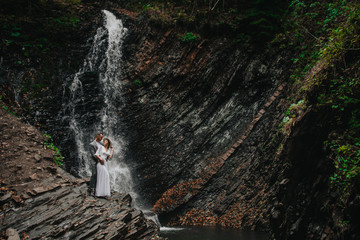 bride and groom in the mountains against the backdrop of a waterfall. mountain wedding