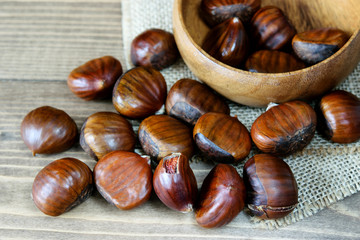 Ripe big chestnuts on the wooden kitchen background closeup. Healthy fruit food.