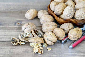 Heap of ripe walnuts in the bowl and on the wooden table closeup. Healthy fruit, antioxidant.